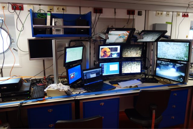 Das ROV-Kontrollzentrum, das in einem der Arbeitsräume unter Deck untergebracht ist. Das 80er-Jahre-Design des Schiffes ist in der Einrichtung deutlich zu erkennen. Beige-weiße Wände, die nur von Bullaugen durchbrochen werden, und Möbel im Blau des Schiffsrumpfes strahlen eine einfache, aber zum Arbeiten ausreichende Atmosphäre aus. Unzählige Bildschirme, Computer, Aufnahmegeräte und Steuereinheiten sind mit einer Vielzahl von Spanngurten gegen die hohe See gesichert. Die Monitore zeigen die Bilder, Navigations- und Orientierungsdaten der Kameras, des Sonars und der Ortung.